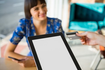 Hand holding a credit card next to the tablet