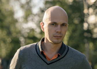 young bald man in the Park on background of trees