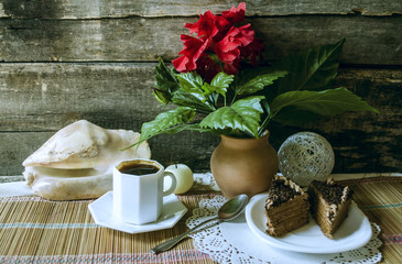 Slices of chocolate, cake black coffee and  Chinese rose in the clay pot  on straw carpet
