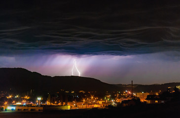 Thunder storm electric lightning strike dark night overcast sky city town landscape 