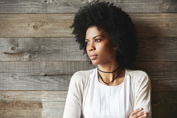Beautiful young African woman, dressed casually, looking away at distance, posing with closed...