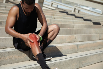 Cropped portrait of dark-skinned jogger in training socks and ru