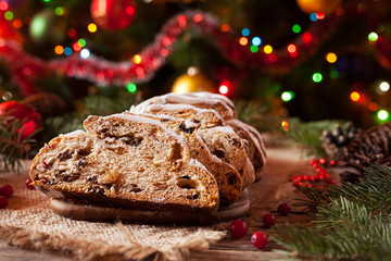 Fototapeta na wymiar Traditional Dresdner German Christmas cake Stollen with Marzipan, Berries Nuts, Cinnamon, Raising on a rustic wooden festive table. Holiday xmas celebration decorations.