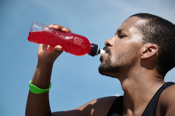 Headshot of exhausted African American athletic runner with sweaty skin wearing sleeveless black...