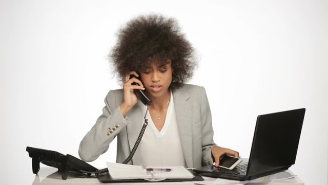 overworked businesswoman in office with telephone, mobilephone and laptop