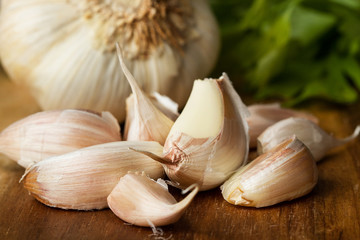 Dientes de ajos con perejil sobre tabla de madera rústica. Vista de frente y de cerca