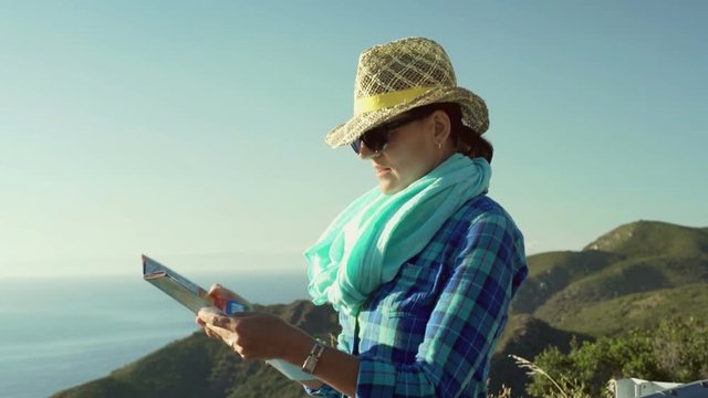 Woman standing on the hill and looking on the map, steadycam shot
