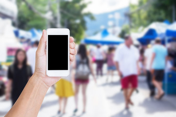 Hand holding mobile phone with blur street market