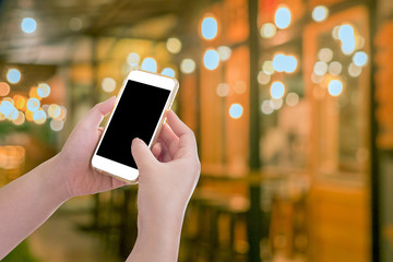 Hand holding mobile phone with blur night light of downtown back