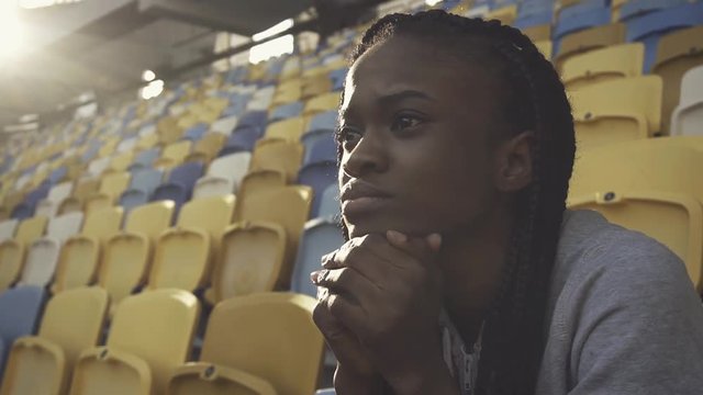 Nervous sporty african-american woman sitting alone in a sports stadium