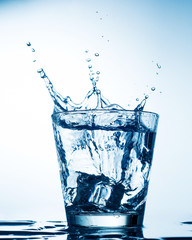 Ice cubes splashing into glass of water
