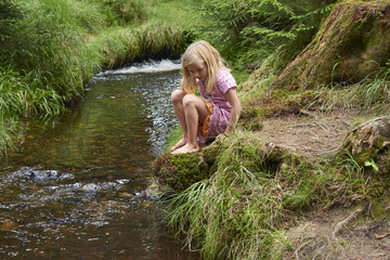 Child cute blond girl playing in the creek. Summer children fun.

