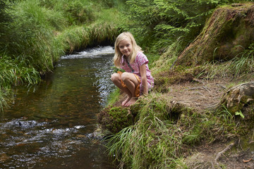 Child cute blond girl playing in the creek. Summer children fun.

