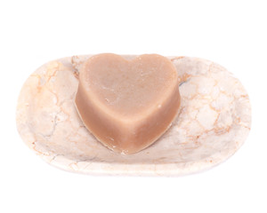Goat milk soap hearth shape on beige marble dish separated on white background