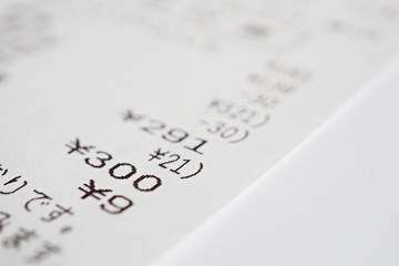 Macro detail of a Japanese paper receipt (white paper bill, sales slip) with a sum of several items and the additional tax as a symbol of market and accountancy in Japan