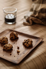 Chocolate chip cookies with the coffee on a wooden plate at the bedroom.
