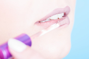 Naklejka premium Close-up of lips with brush applying glossy lipgloss