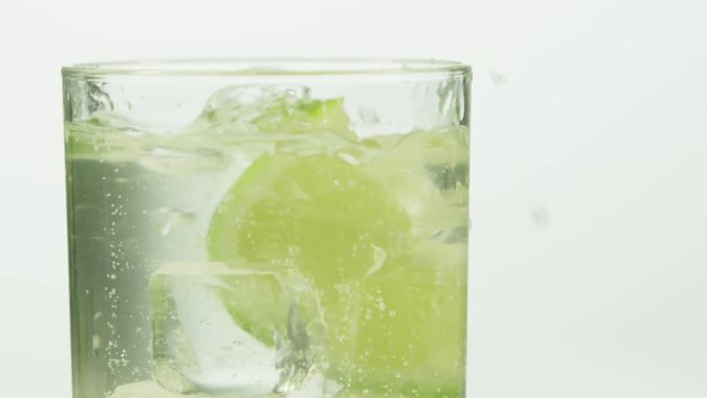 Closeup of lime dropping into carbonated drink