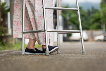 senior woman using a walker on street.