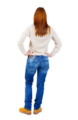 back view of standing young beautiful woman. girl in a white blouse standing with his hands on his belt.