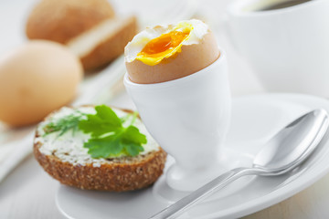Breakfast with perfect soft boiled egg, sandwich with cheese and coffee on a table. Traditional homemade food.