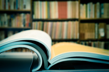 Piles of books and magazines on background of book shelf