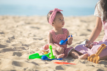 baby girl with mother at the beach play with toys on the sand