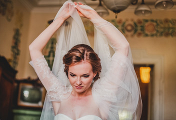 Close up portrait of pretty bride in hotel room with flower bouquet