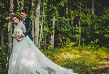 Fototapeta premium bride and groom kissing and embracing in the forest