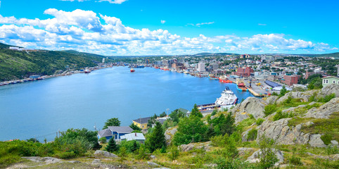 Panoramic views with bight blue summer day sky with puffy clouds over the harbour and city of St. John's Newfoundland, Canada. - 119350219