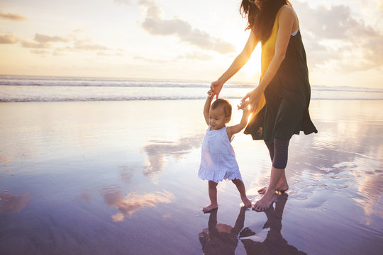 mother is teaching her daughter walks on the beach
