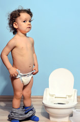 Baby toddler sitting near the potty and scared. Cute kid potty training for pee and poo