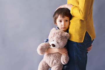 Sad little child, boy, hugging his mother at home