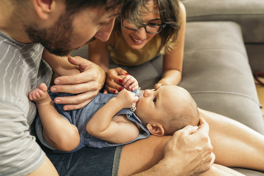 Parents playing with their son while sitting on sofa at home