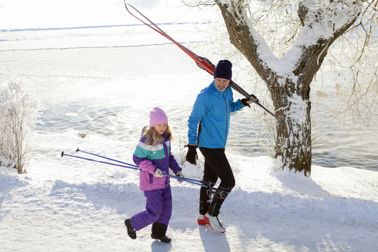 Father with daughter walking with skis