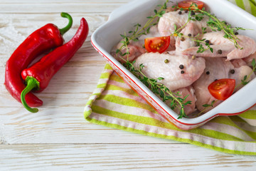 Raw chicken wings with thyme, chili, pepper and tomatoes