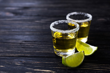 Gold tequila with lime and salt on dark table