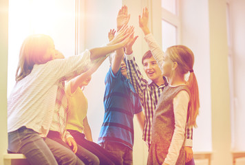 group of smiling school kids making high five