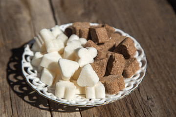 There is a figured brown and white sugar on a porcelain white saucer.There is a saucer on the  wooden surface.