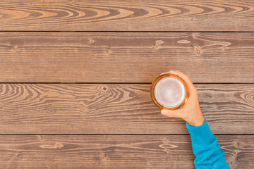 Male hand holding beer glass over wooden table