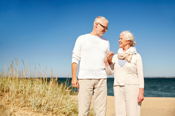 happy senior couple talking on summer beach