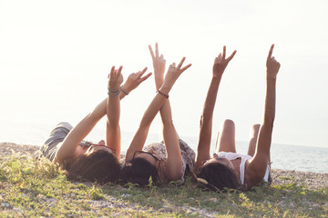 young women lying in the meadow raise their arms in a sign of friendship
