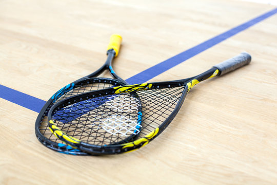 Yellow and blue tennis rackets are lying on wooden court background - sport, fitness, healthy lifestyle and objects concept