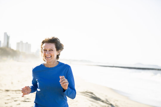 Happy mature woman running on beach