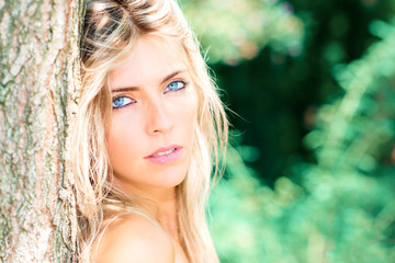 Portrait of beautiful blond girl with blue eyes in nature