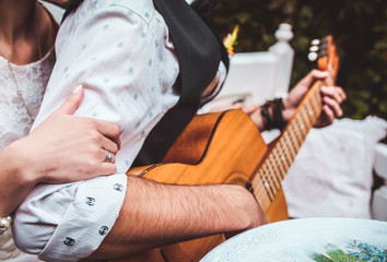 Romantic couple sitting outdoors at sunset with the man playing the guitar.