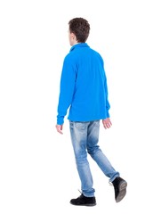 Fototapeta premium Back view of going handsome man. Curly boy in blue jacket standing on one leg.