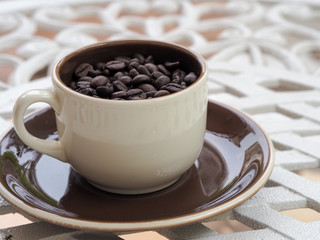 one cup of coffee beans and plate on the white tabel background