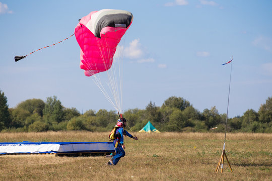 skydiver with pink gray parachute landed in  field