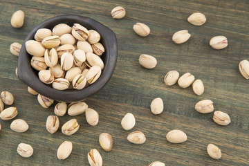 Pistachios in the bowl on wooden background